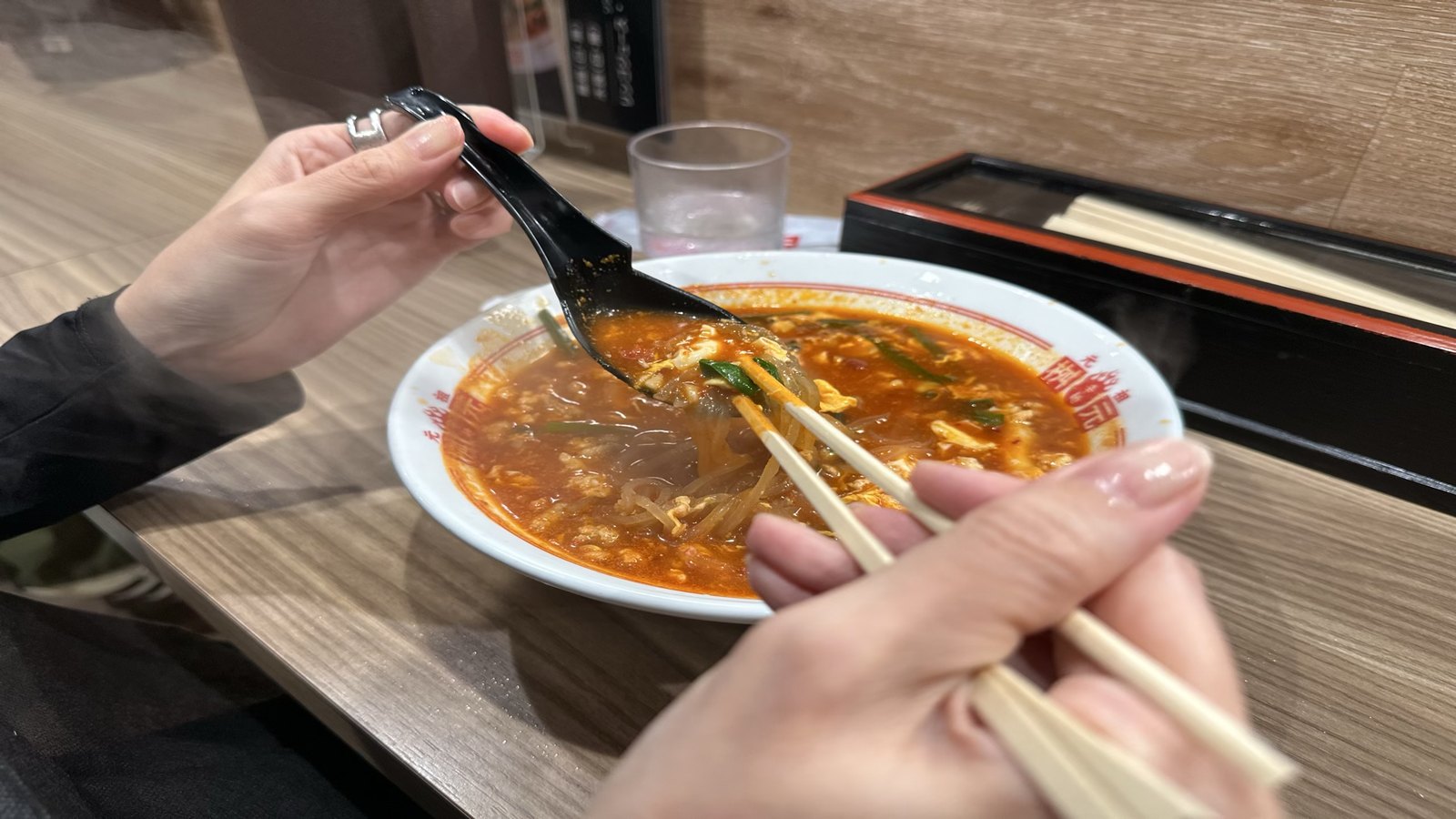 トマト辛麺のスープをレンゲですくったところ